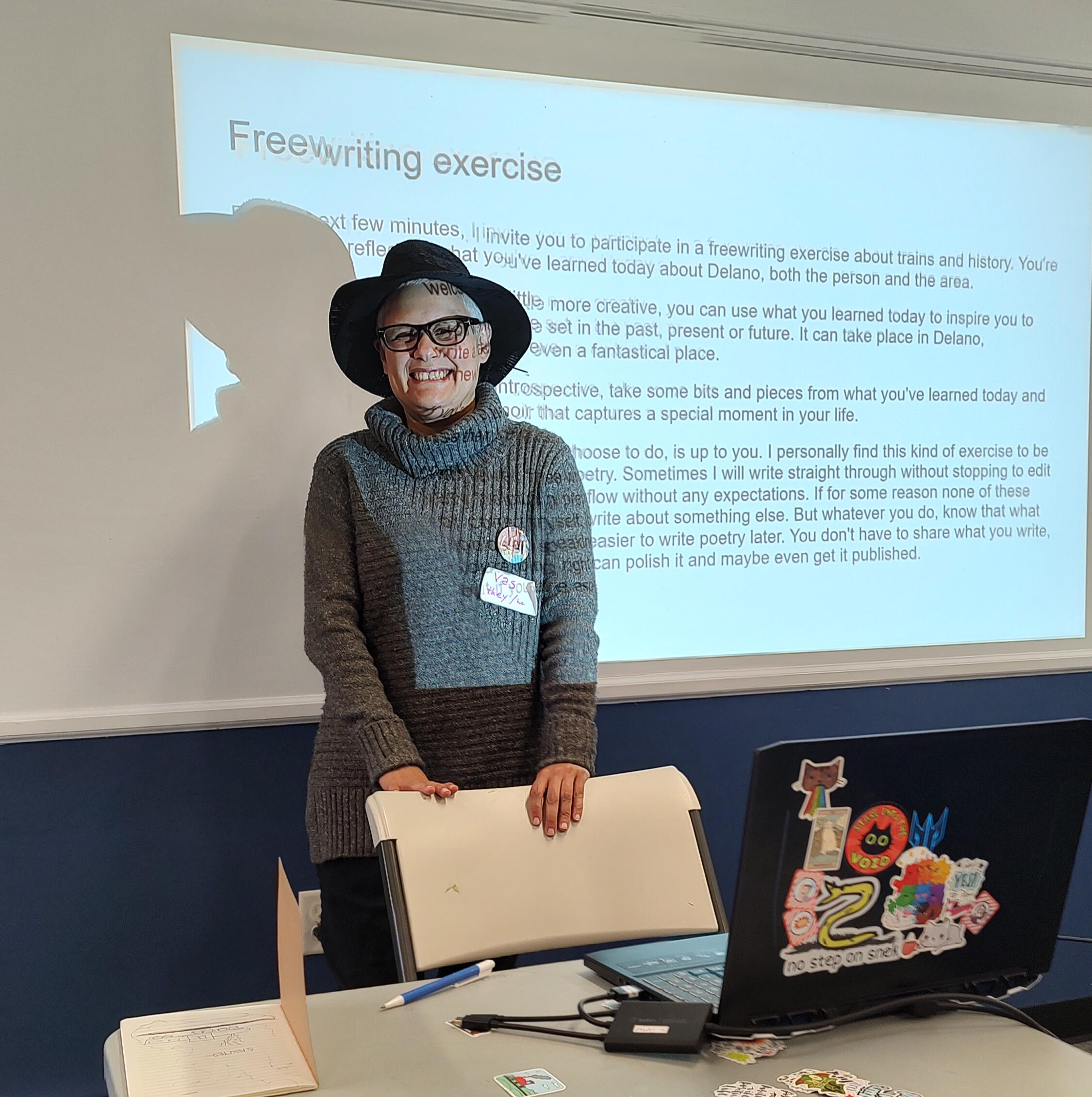 Vas giving a historical poetry presentation. Vas in front of a slide projector